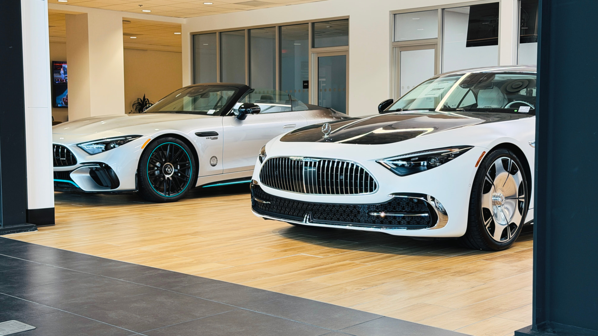 Two white Mercedes cars displayed side by side in a bright showroom